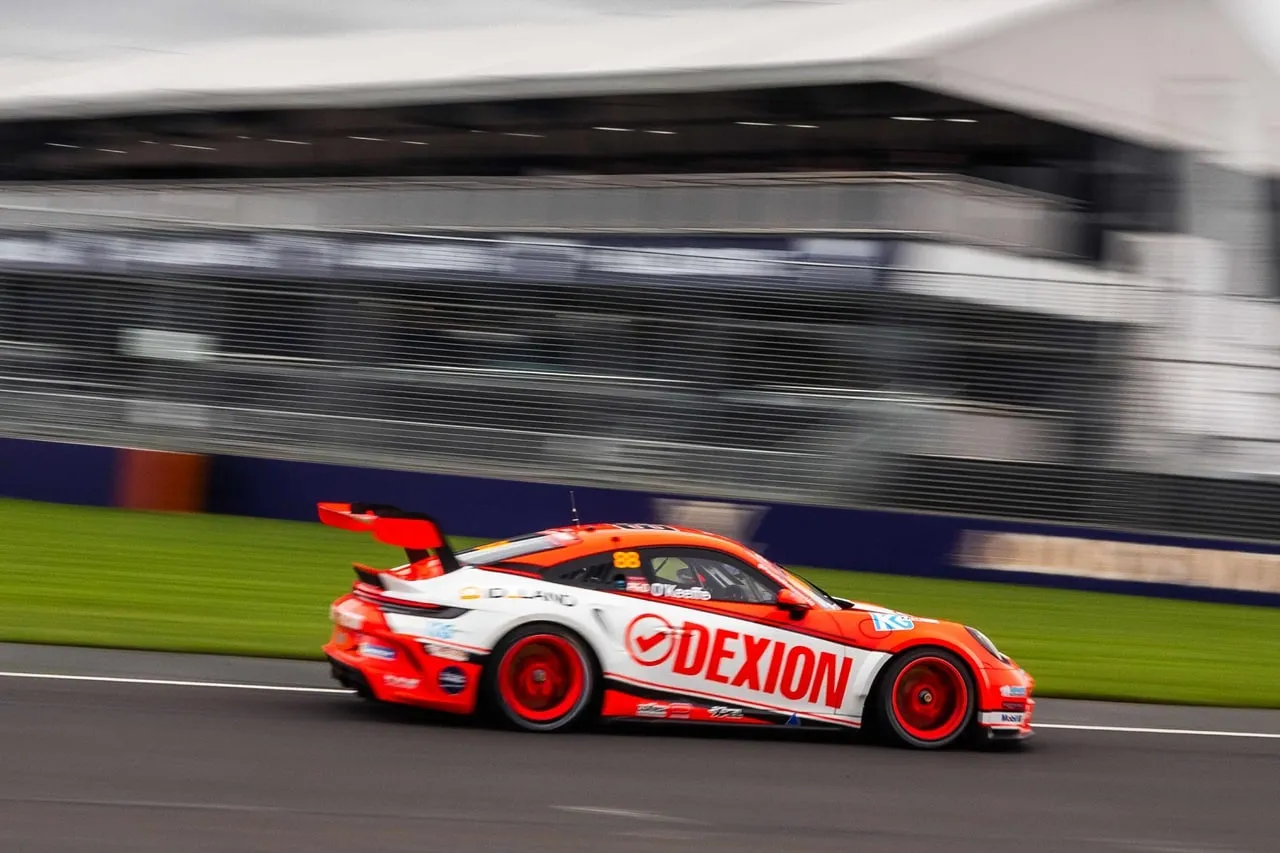 Dexion Porsche #88 speeding past a grandstand with motion blur