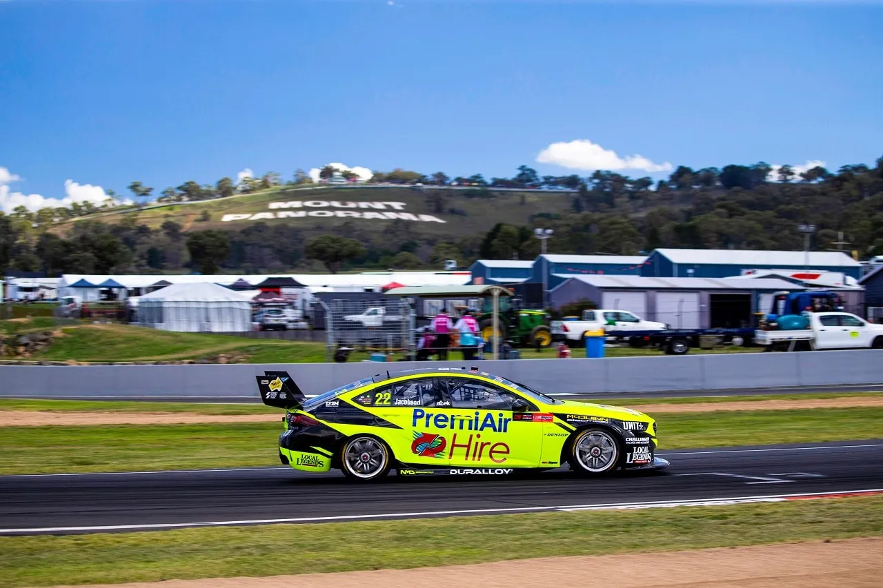 The yellow #22 PremiAir Hire Holden ZB Commodore on track at Mount Panorama with the hillside lettering behind