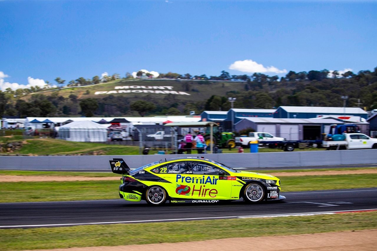 The yellow #22 PremiAir Hire Holden ZB Commodore on track at Mount Panorama with the hillside lettering behind