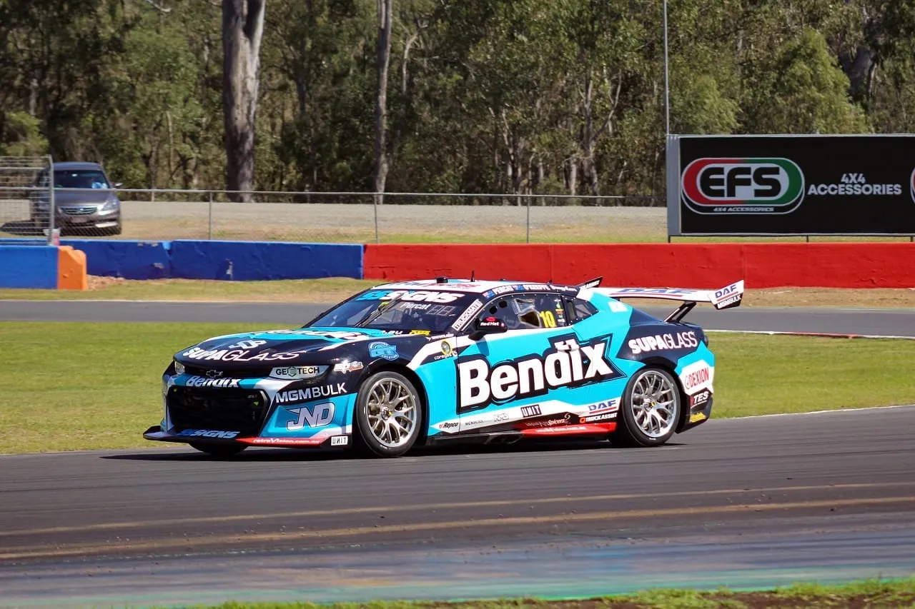 Bendix Supagas Chevrolet Camaro Supercar cornering on a circuit with trees behind