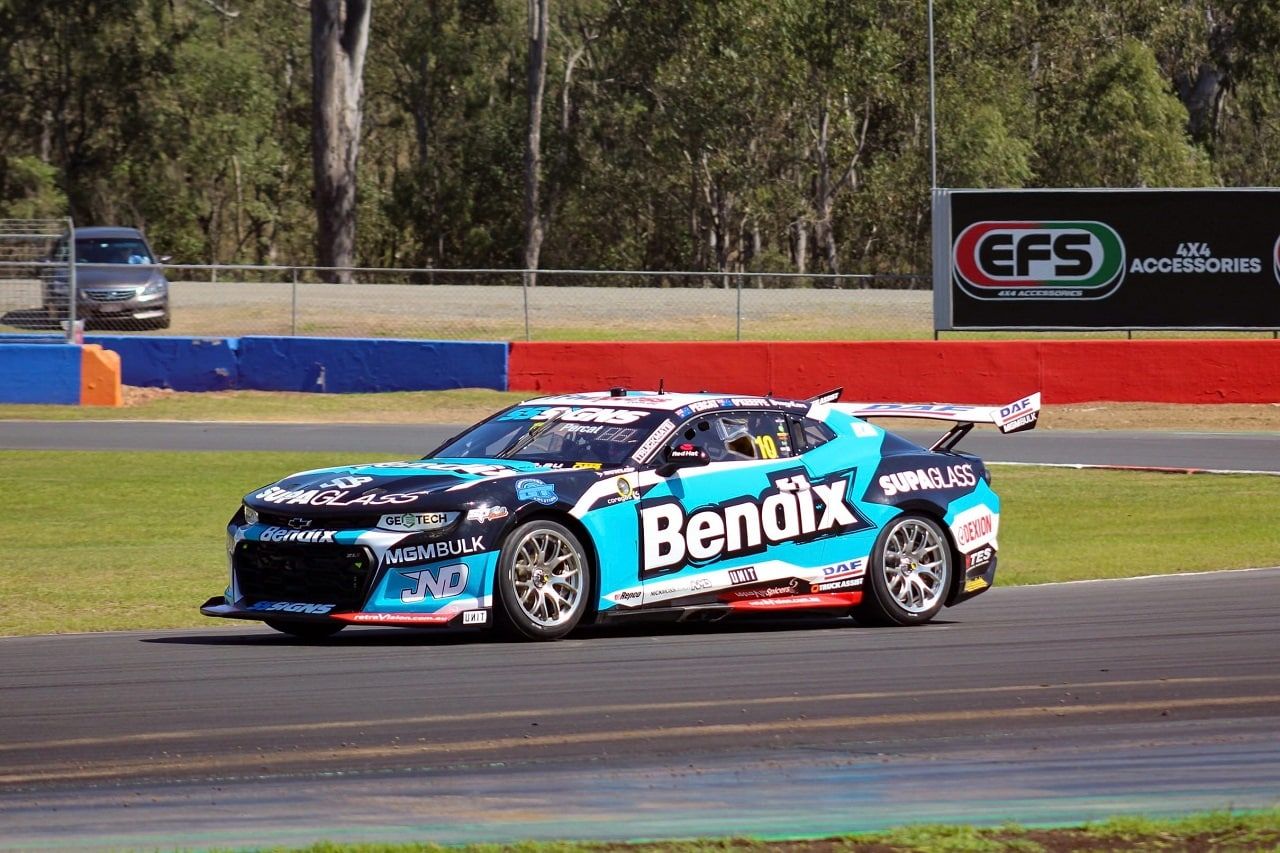 Bendix Supagas Chevrolet Camaro Supercar cornering on a circuit with trees behind
