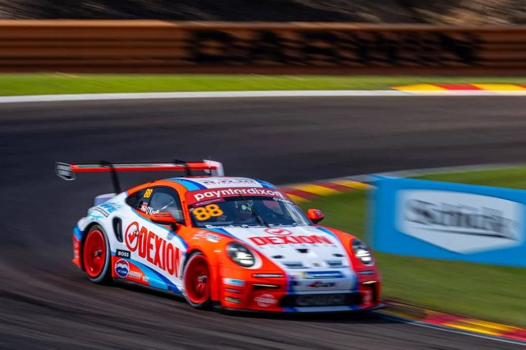 Number 88 Dexion Porsche Carrera Cup car cornering at speed beside a blue advertising board