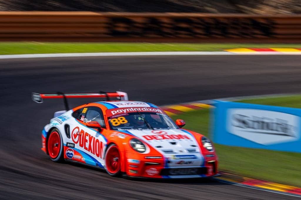 Number 88 Dexion Porsche Carrera Cup car cornering at speed beside a blue advertising board