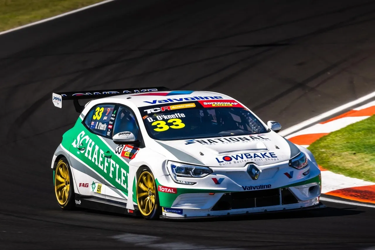 The white and green #33 Schaeffler Renault Megane TCR car cornering on track with orange and white kerbs