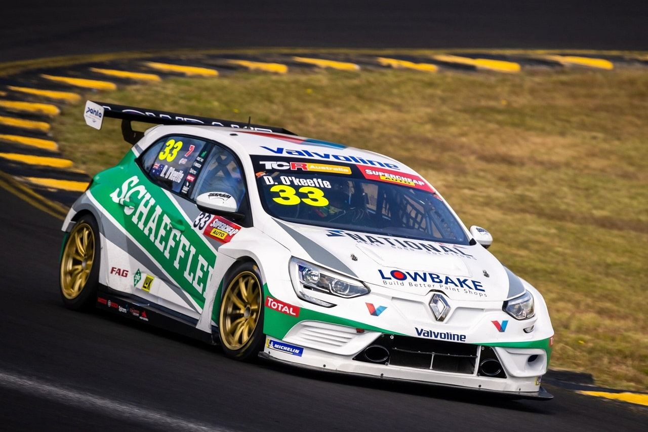 The white and green #33 Schaeffler Renault Megane TCR car on track with yellow and black kerbs behind, driver named D. O’Keeffe on the windscreen