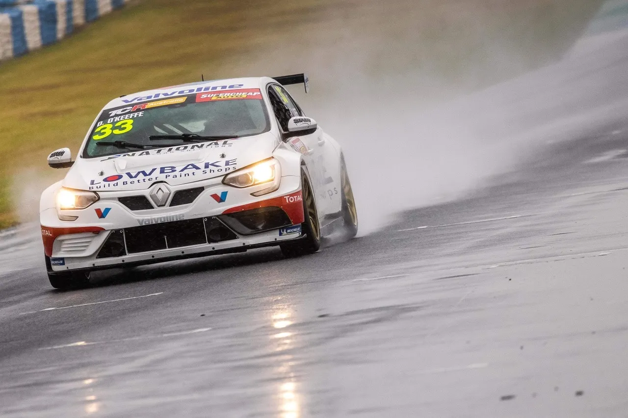 The white #33 Lowbake Renault Megane TCR car driving through spray on a wet track with headlights on