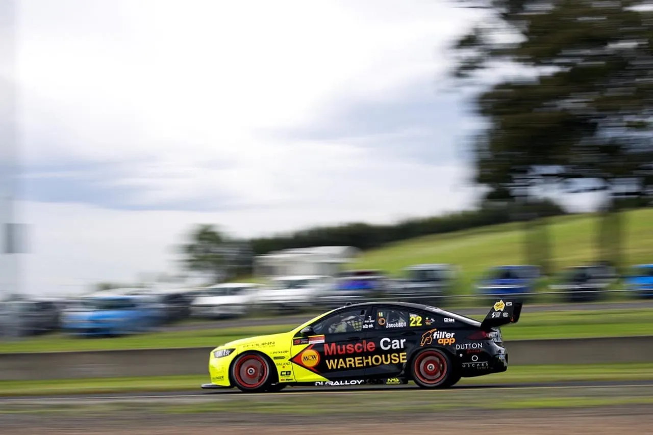 The #22 Muscle Car Warehouse Holden Commodore Supercar in yellow and black speeding past with motion blur