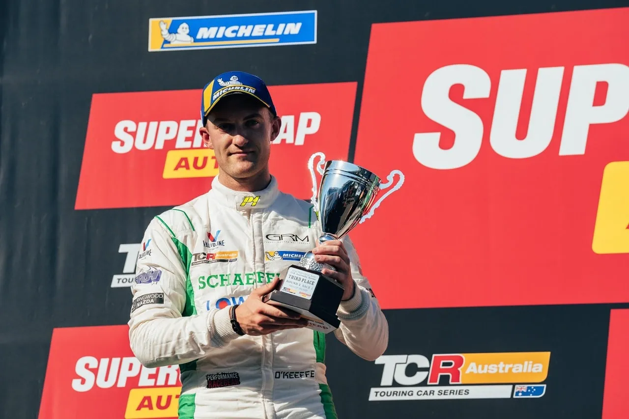 Dylan O’Keeffe holding a third-place trophy on the podium in front of Supercheap Auto and TCR Australia signage