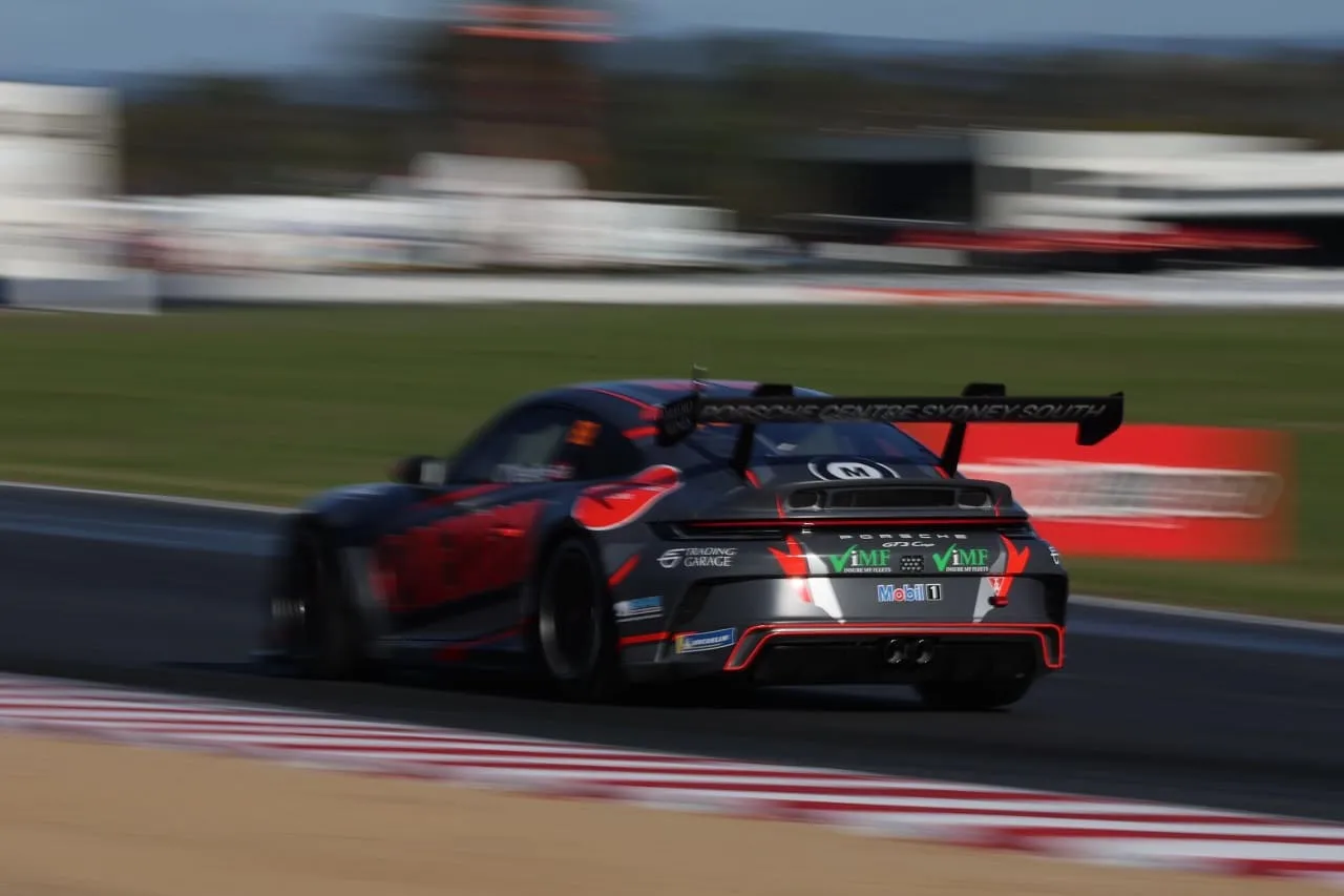 Rear view of a Porsche GT3 Cup car in motion blur on track past red and white kerbs