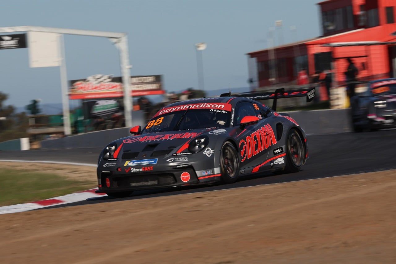 The #88 Dexion Porsche GT3 Cup car cornering on track with a red building behind