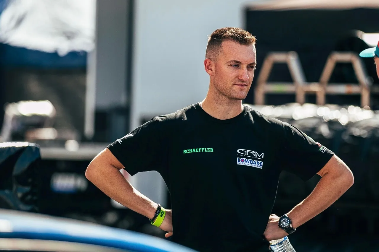 Dylan O’Keeffe in a black Schaeffler and Lowbake T-shirt standing with hands on hips in the pits