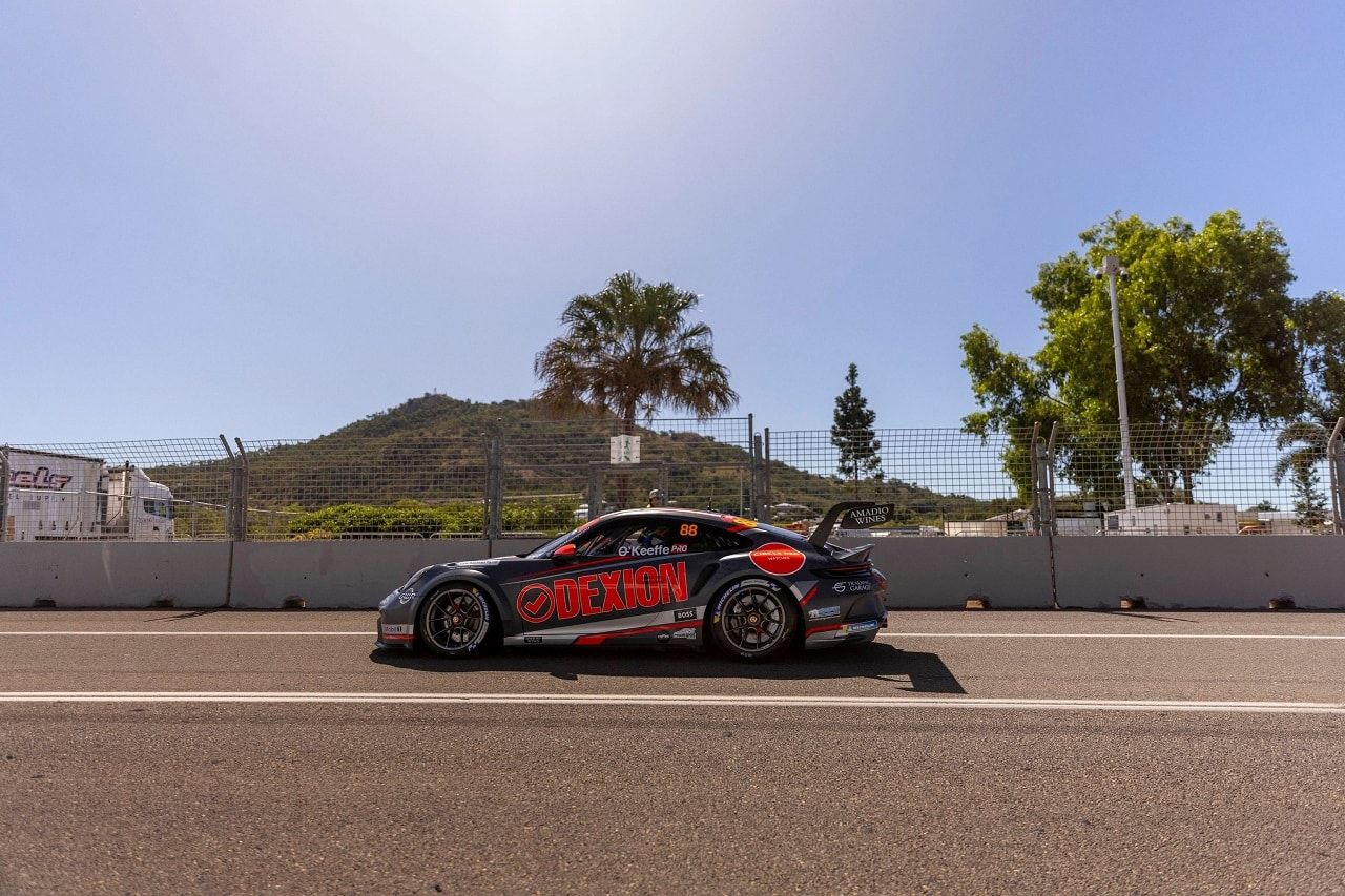 The #88 Dexion Porsche GT3 Cup car in side profile beside a concrete wall with a hill behind