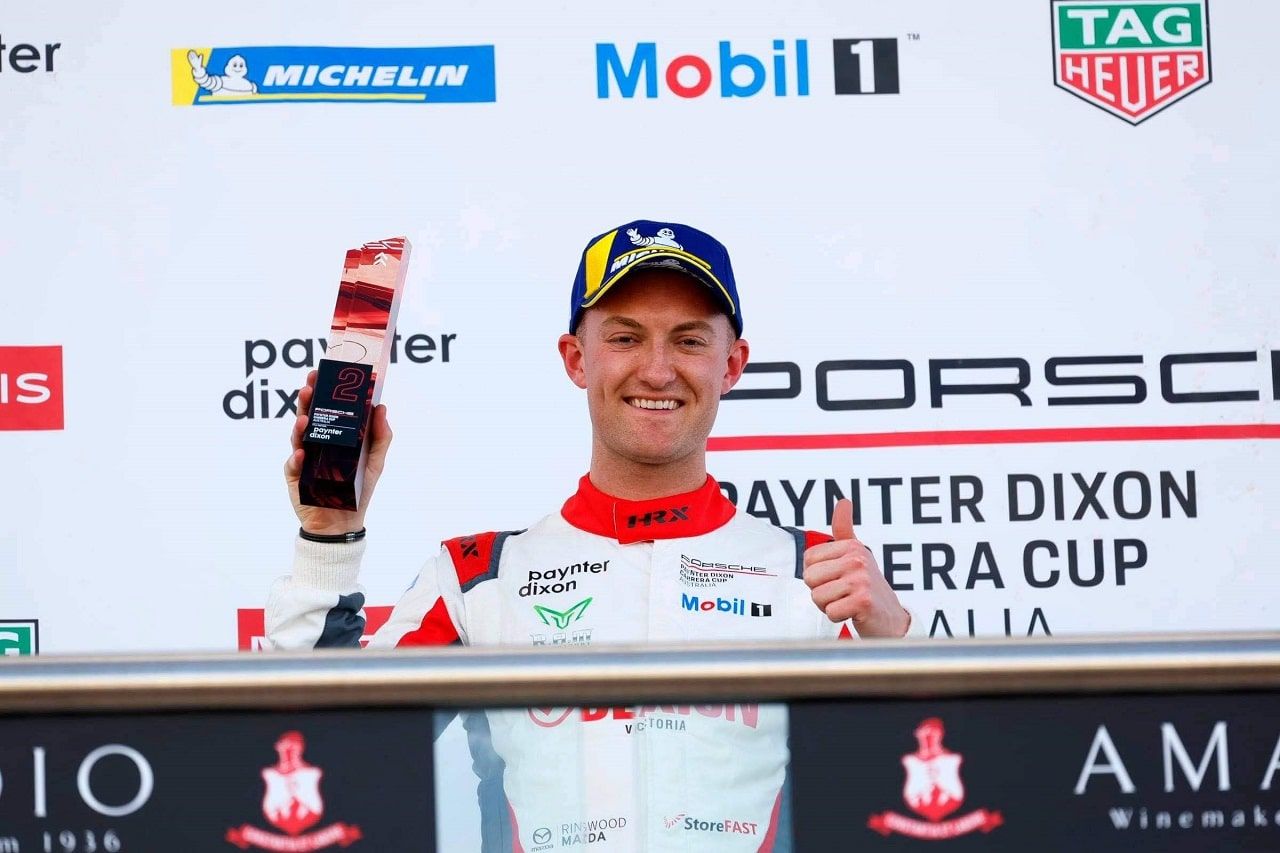 Dylan O’Keeffe smiling on the podium, holding a second-place trophy and giving a thumbs up