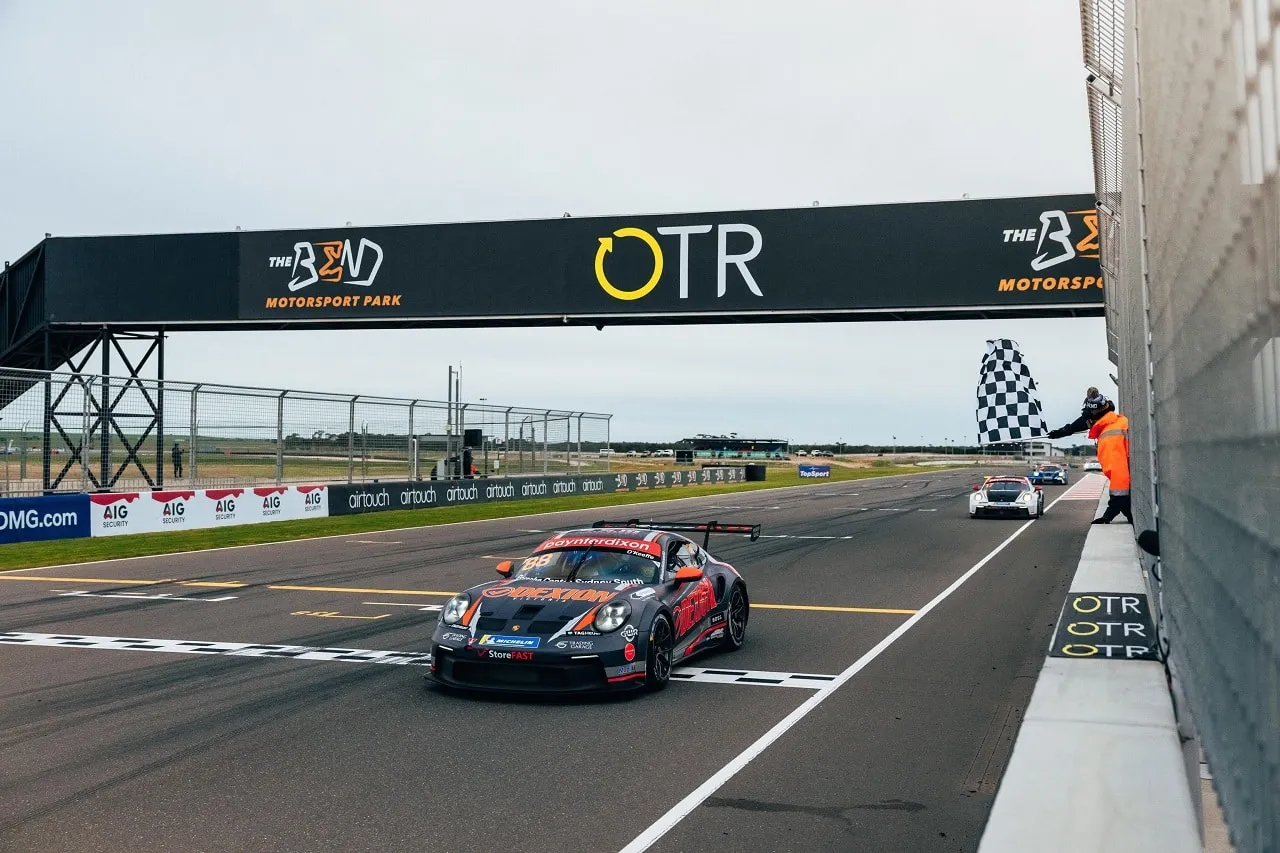 The #88 Dexion Porsche GT3 Cup car takes the chequered flag beneath The Bend Motorsport Park gantry