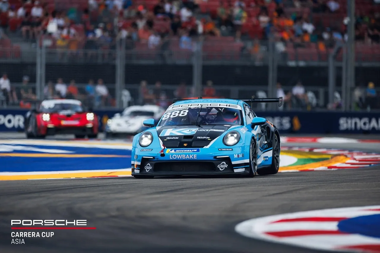 Blue and black National-liveried Porsche 911 GT3 Cup car #888 on a street circuit with a crowd behind