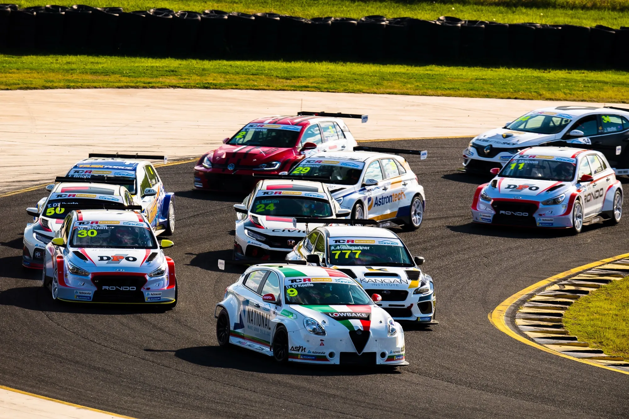 The #9 Alfa Romeo Giulietta TCR car in the middle of a tightly bunched field on the opening lap of a TCR race