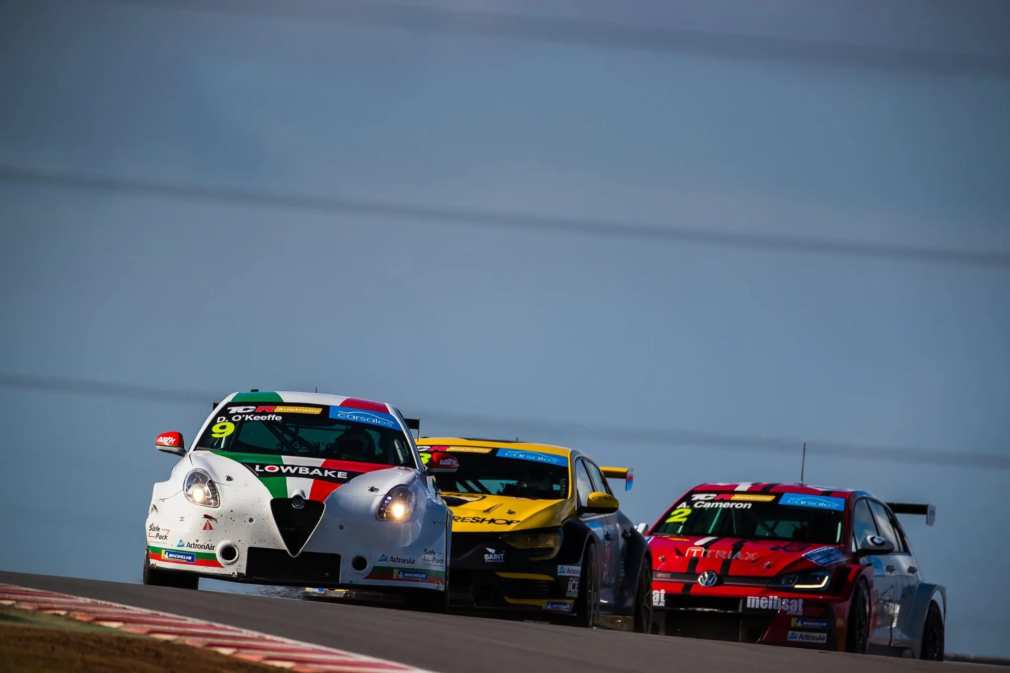 The white #9 Lowbake Alfa Romeo TCR car racing ahead of a yellow Renault and a red Volkswagen TCR car