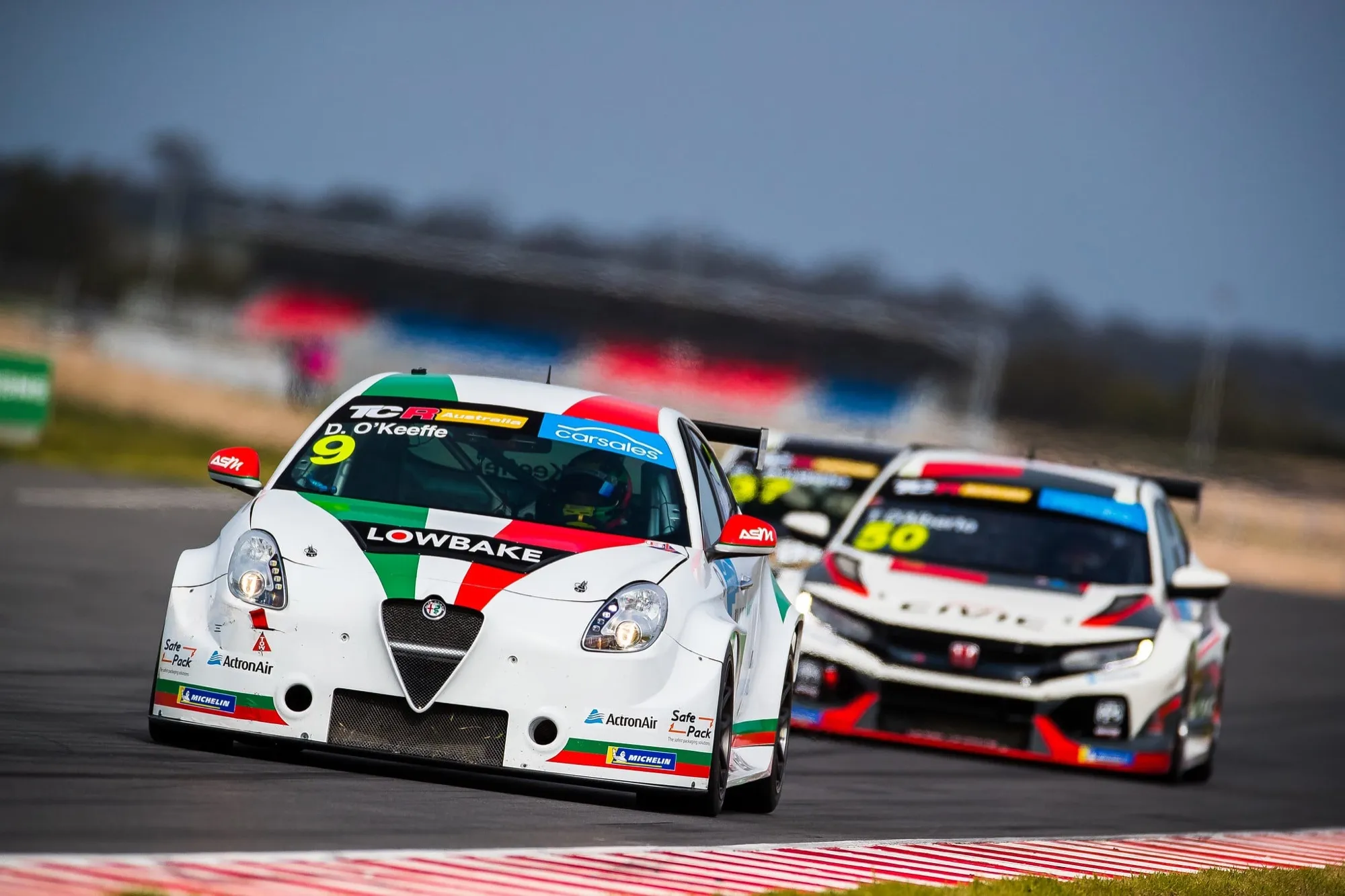The #9 Lowbake Alfa Romeo Giulietta TCR car racing ahead of a white Honda Civic TCR car
