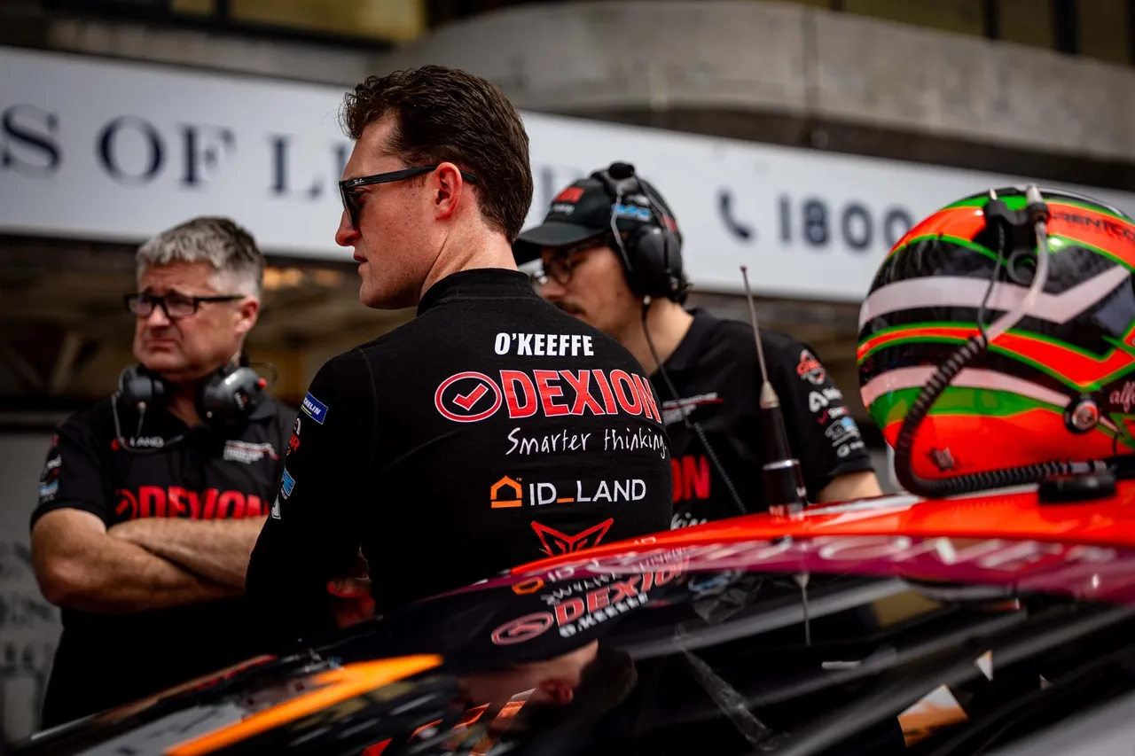 Dylan O’Keeffe in sunglasses and his Dexion race suit beside the car, crew members in headsets behind him