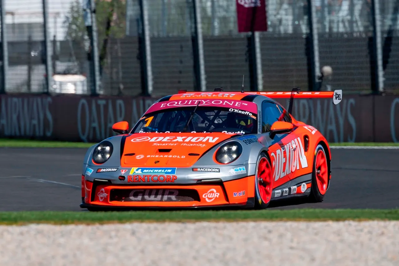 Dexion Porsche 911 GT3 Cup car #1 on track with a grandstand and Qatar Airways signage behind