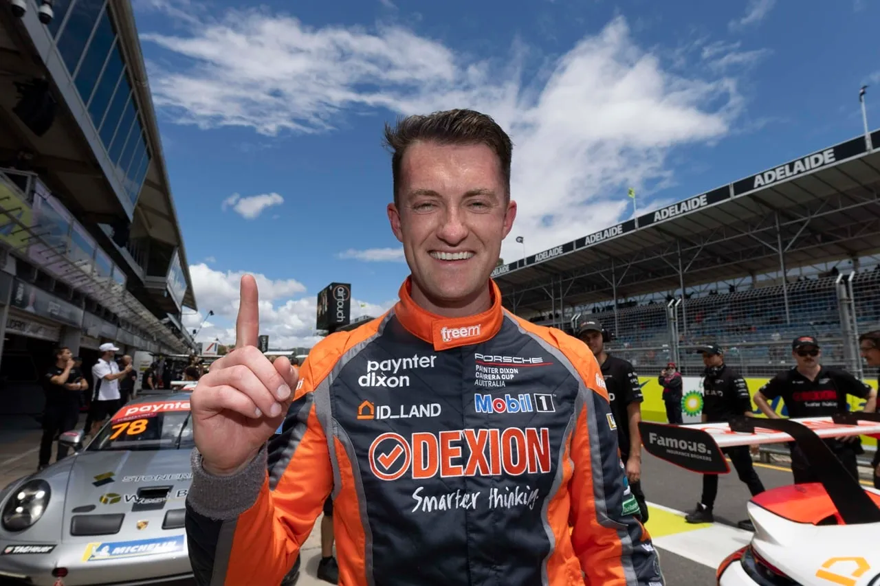Dylan O’Keeffe in his Dexion race suit smiling and holding up one finger