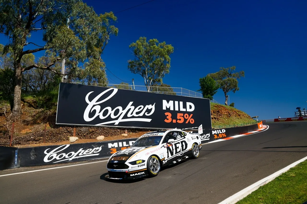 The NED Whisky Ford Mustang Supercar on track under a bright blue sky in front of Coopers Mild signage