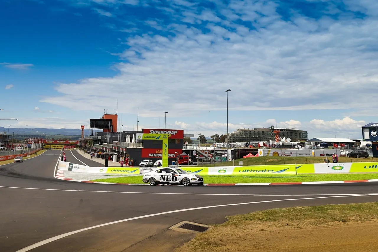 The NED Whisky Ford Mustang Supercar on track at Mount Panorama with the pit straight and grandstands behind