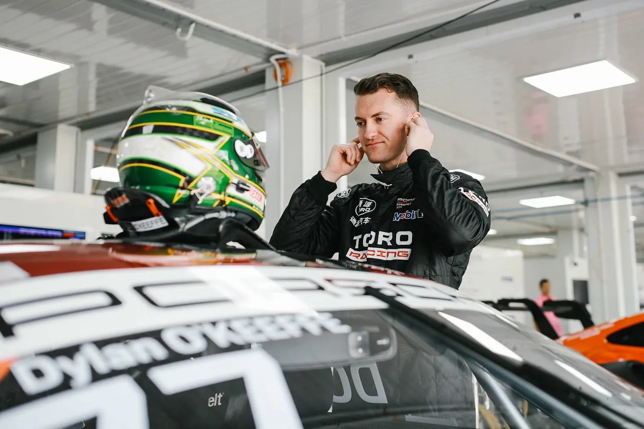 Dylan O’Keeffe in a Toro Racing suit beside the car, his name across the windscreen banner