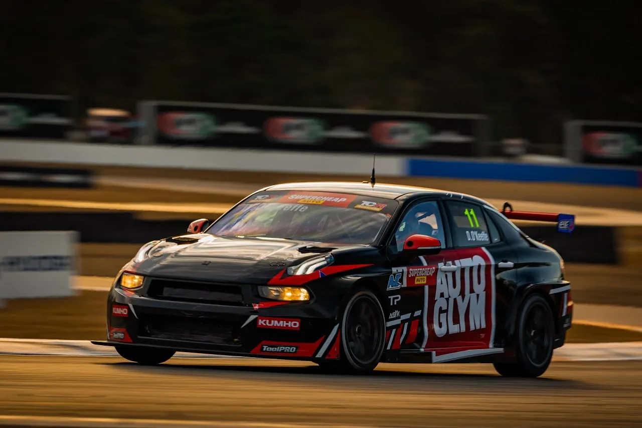 Black number 11 Autoglym Lynk & Co TCR car with its headlights on at dusk on track