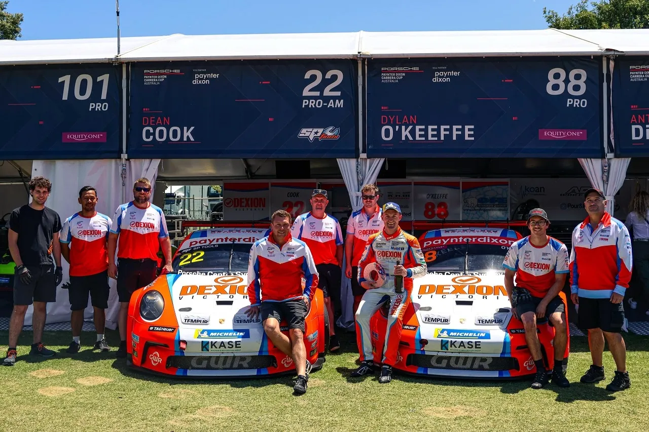 RAM Motorsport crew in Dexion shirts with two Porsche Carrera Cup cars, garage signs reading Dean Cook and Dylan O’Keeffe