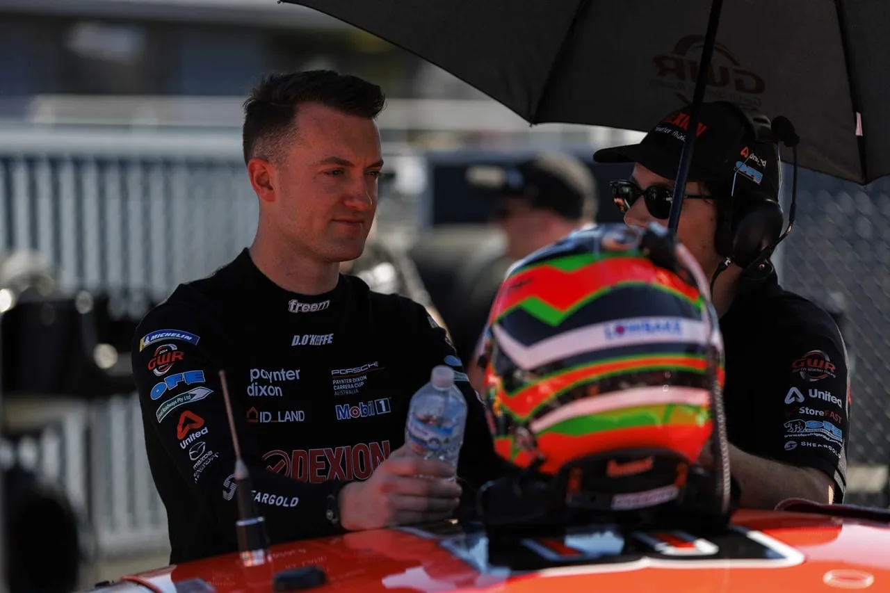 Dylan O’Keeffe holding a water bottle beside his helmet on the grid under a GWR umbrella