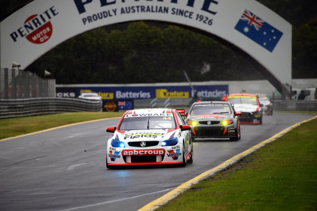 The #44 apbgroup Commodore Supercar leading other cars on a wet track under the Penrite Oil arch at Sandown