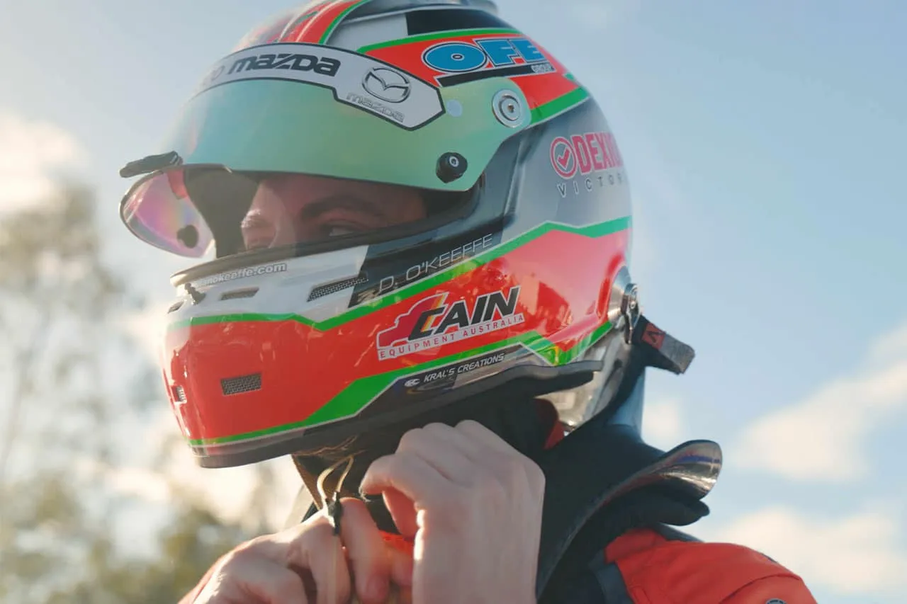 Close-up of Dylan O’Keeffe in his helmet, adjusting the chin strap