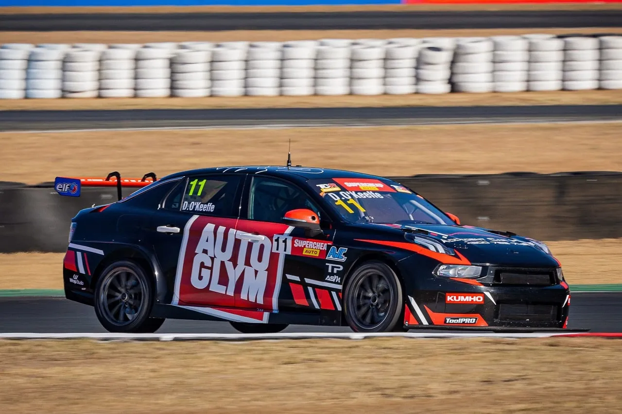 Black number 11 Autoglym Lynk & Co TCR car at speed in front of a tyre wall