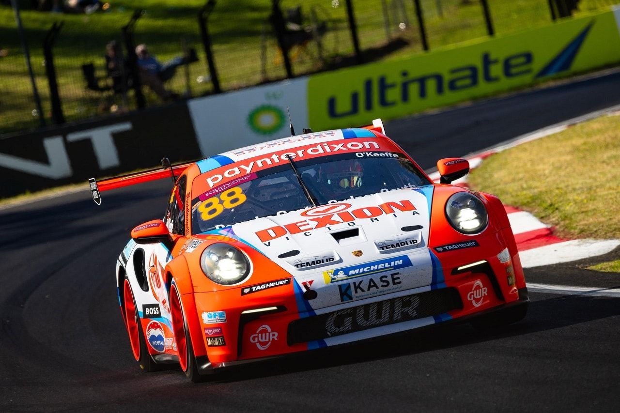 An orange and silver Dexion Porsche 911 GT3 Cup car cornering past the bp Ultimate barrier