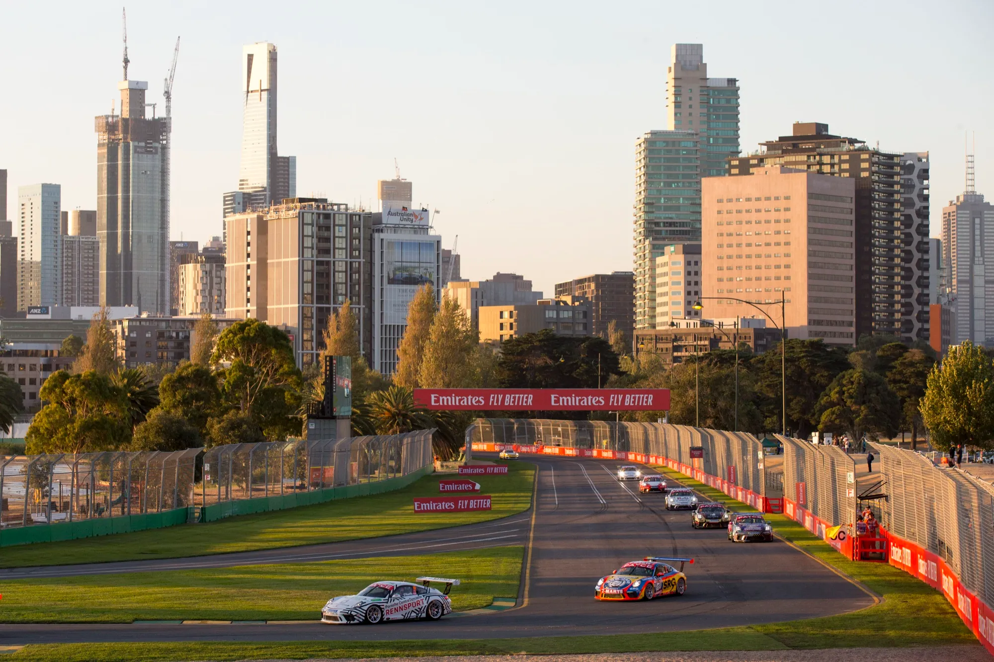 Porsche Carrera Cup cars racing on a straight with the Melbourne city skyline in the background