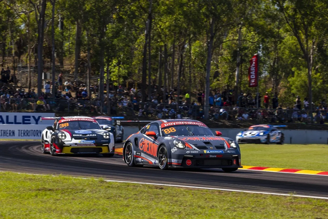 The #88 Dexion Porsche GT3 Cup car leads a pack of Porsches through a corner as spectators watch from the trees