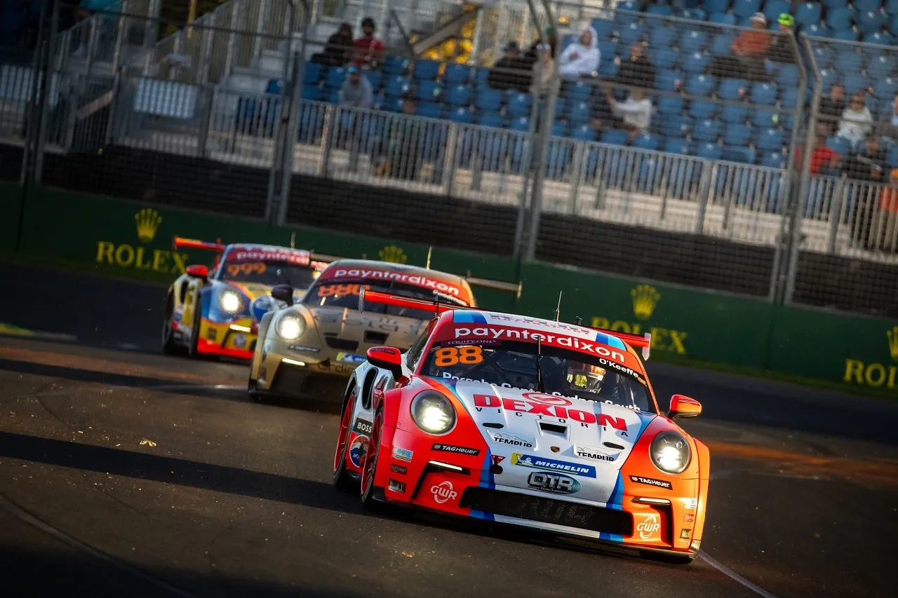 Number 88 Dexion Porsche Carrera Cup car leads two rivals beneath Rolex signage at the Grand Prix circuit