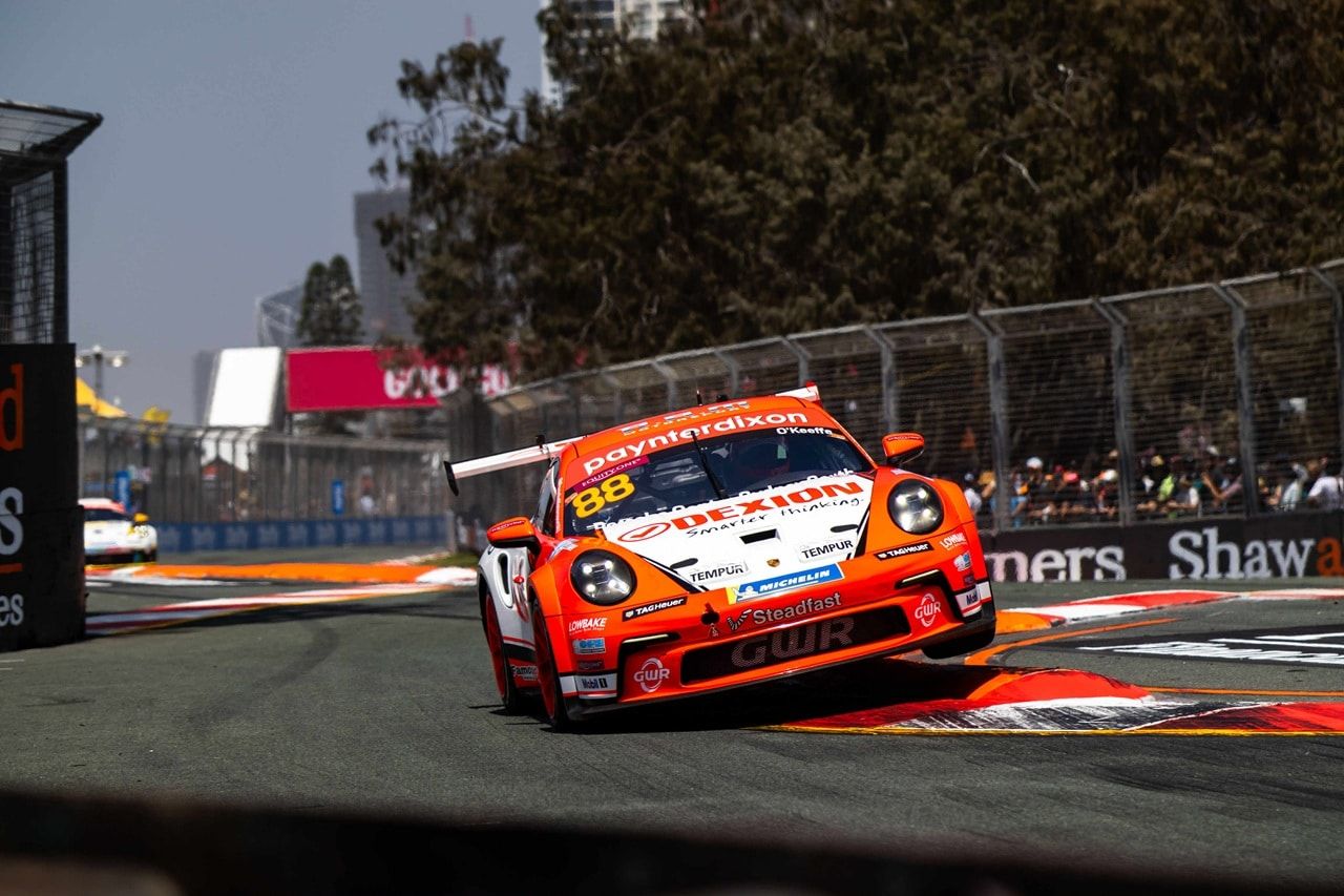 Dexion Porsche #88 at speed on a street circuit, with spectators behind the fence