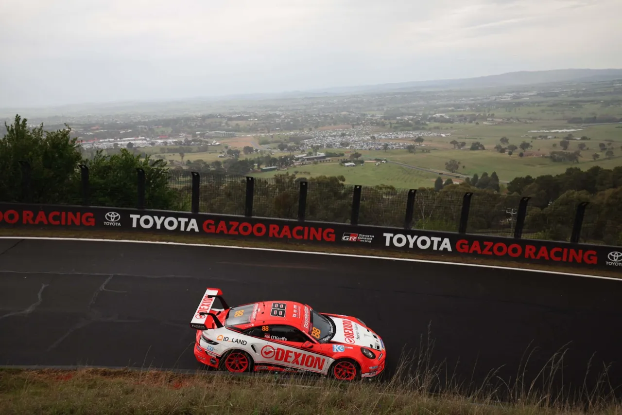 The Dexion Porsche climbing Mount Panorama past the Toyota Gazoo Racing wall, the Bathurst countryside spread out below