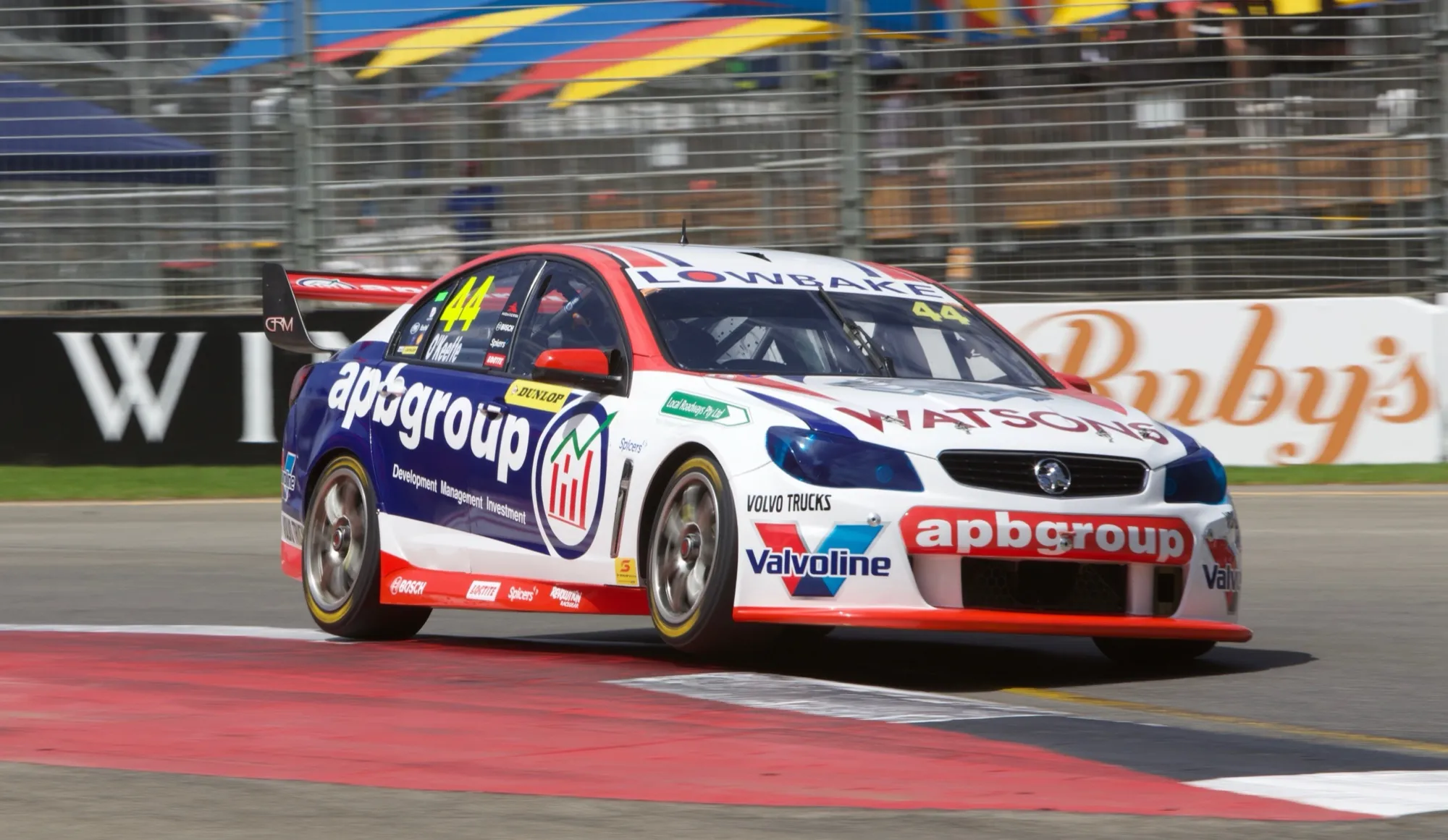 The #44 apbgroup Watsons Commodore Supercar riding a kerb on a street circuit