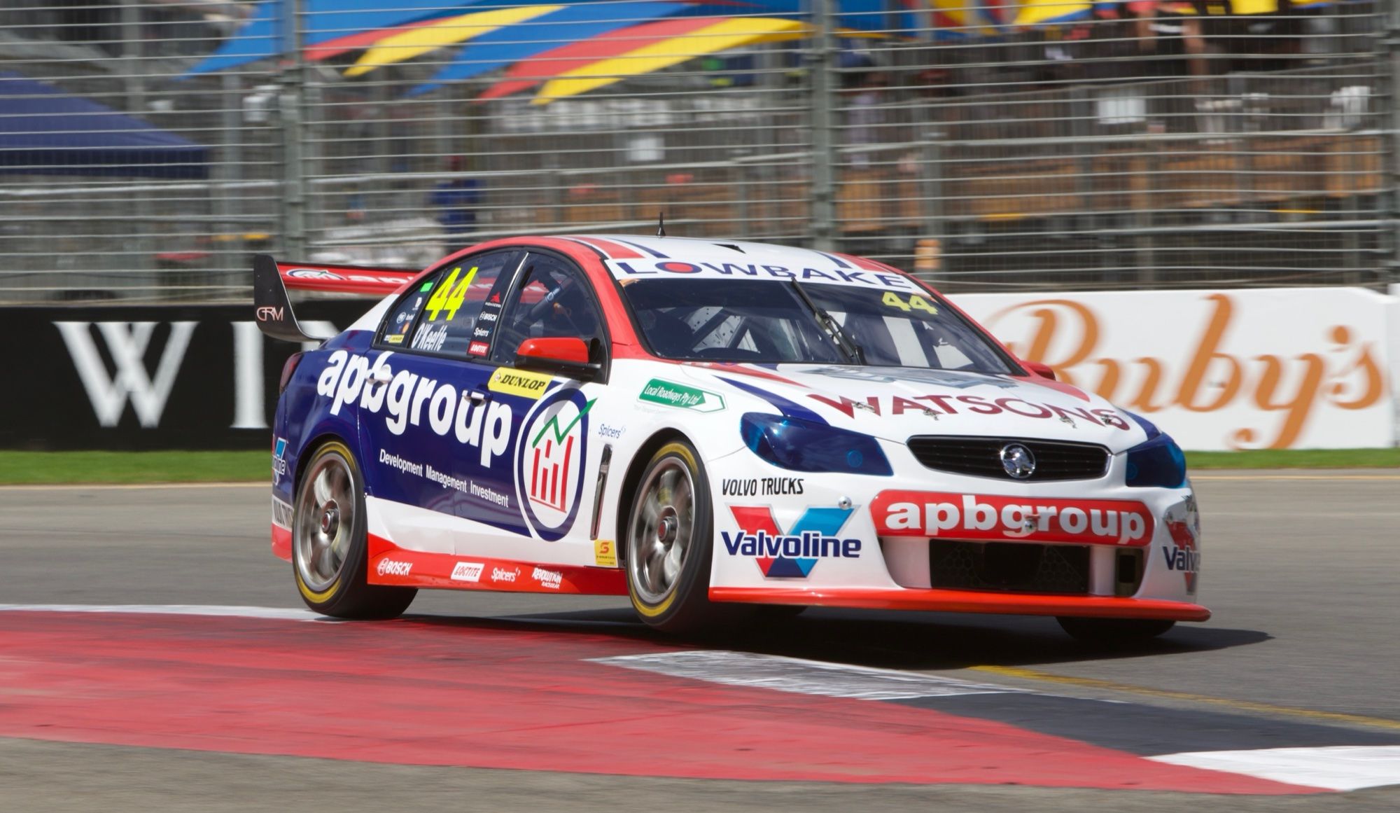 The #44 apbgroup Watsons Commodore Supercar riding a kerb on a street circuit