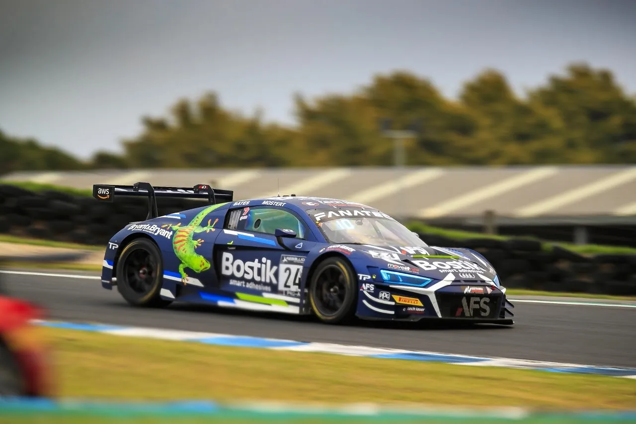 The blue #24 Bostik Audi R8 GT3 car with a green gecko graphic cornering with motion blur