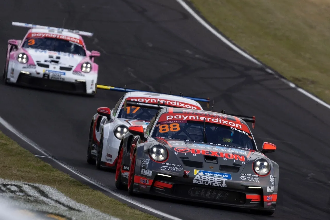 The number 88 Dexion Porsche 911 GT3 Cup car racing ahead of a white Porsche and a pink and white Porsche