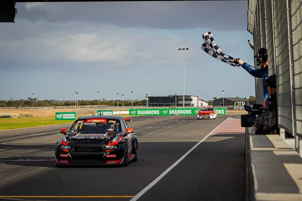 Black number 11 Autoglym Lynk & Co TCR car takes the chequered flag from a marshal at the finish line