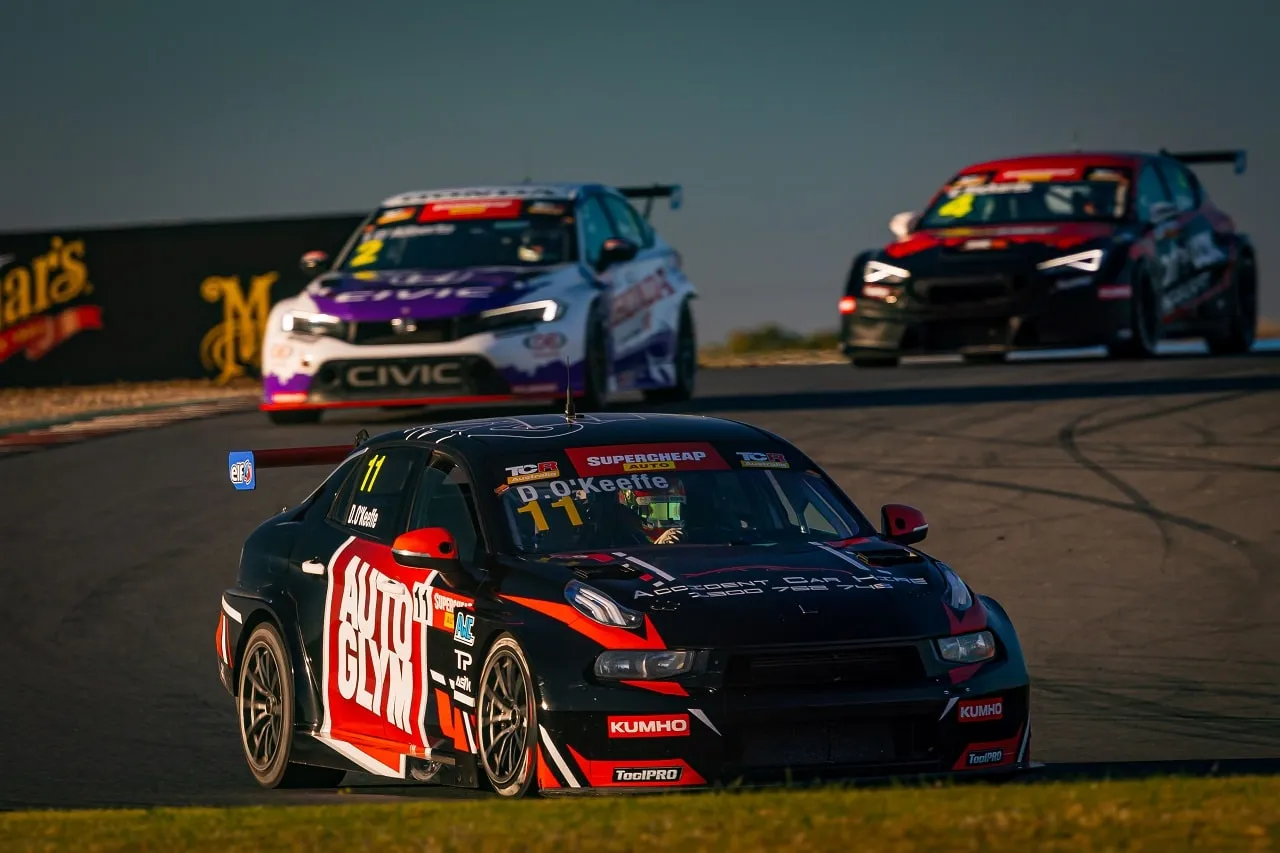 Black number 11 Autoglym Lynk & Co TCR car cornering ahead of two rival TCR cars at dusk