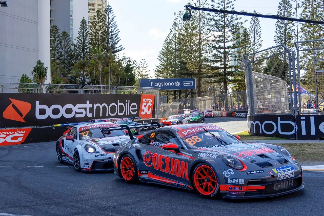 The grey Dexion Porsche 911 GT3 Cup car, number 88, racing on the Gold Coast street circuit past Boost Mobile signage