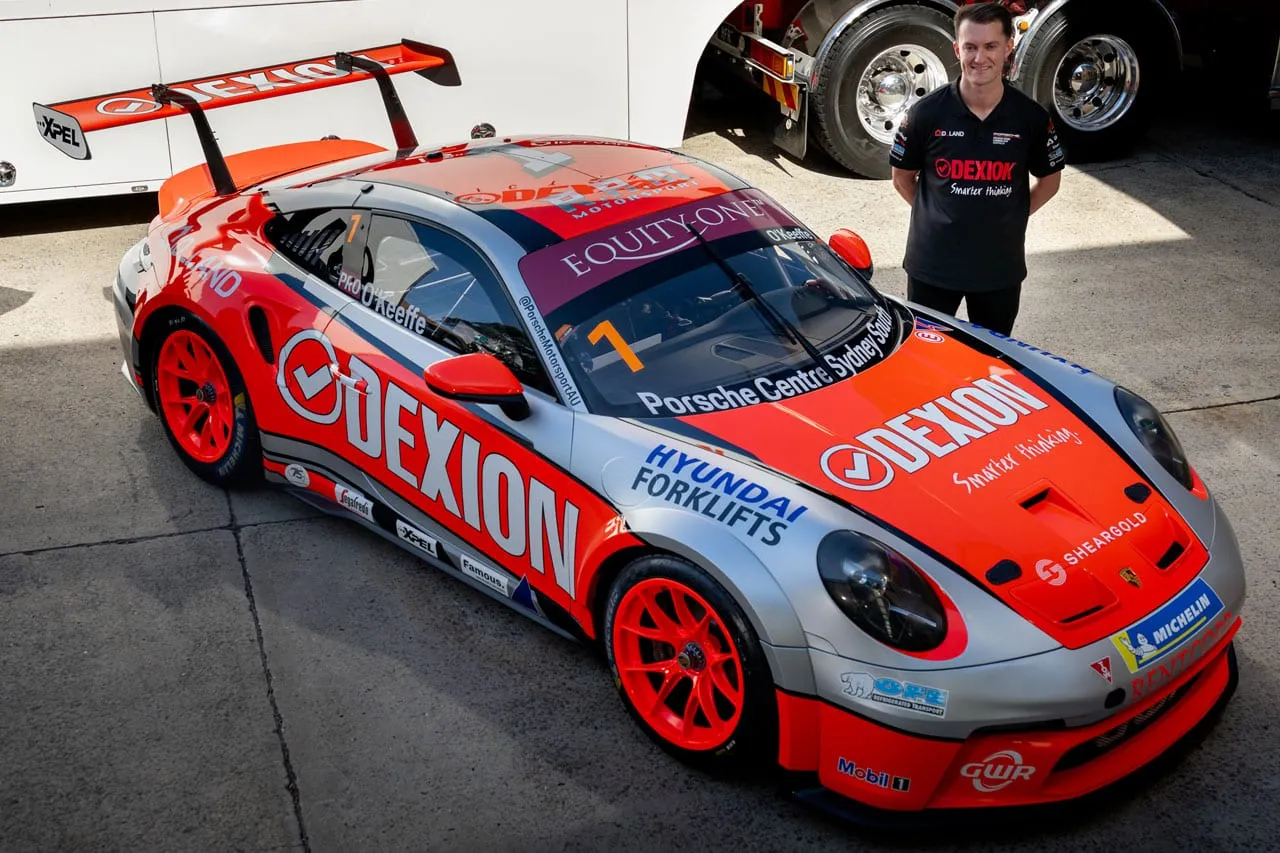 The new silver and orange Dexion Porsche 911 GT3 Cup car with a team member standing behind it