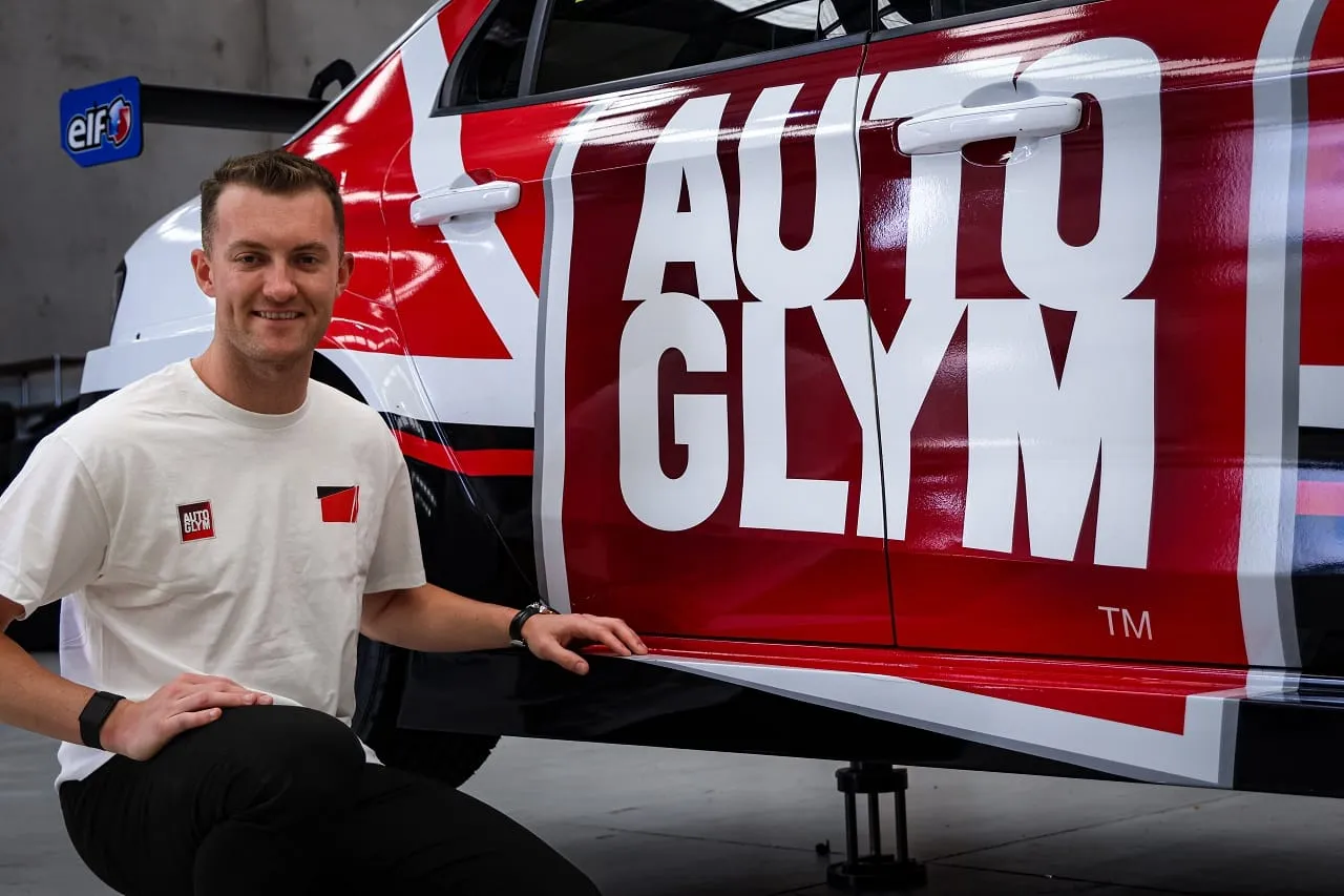 Dylan O’Keeffe crouching beside the door of the red and white Autoglym Lynk & Co TCR car