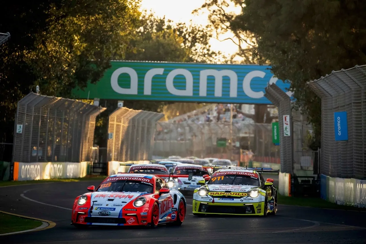 Number 88 Dexion Porsche Carrera Cup car leads other Porsches under an Aramco gantry at golden hour